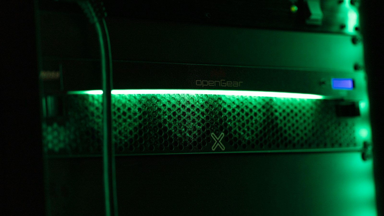 Close-up of a server rack lit by a green indicator light